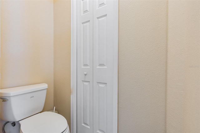 bathroom featuring a closet, a textured wall, and toilet