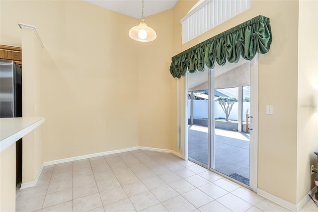 unfurnished dining area with light tile patterned flooring and baseboards