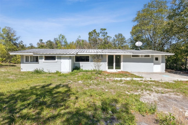 ranch-style home with metal roof and a front lawn