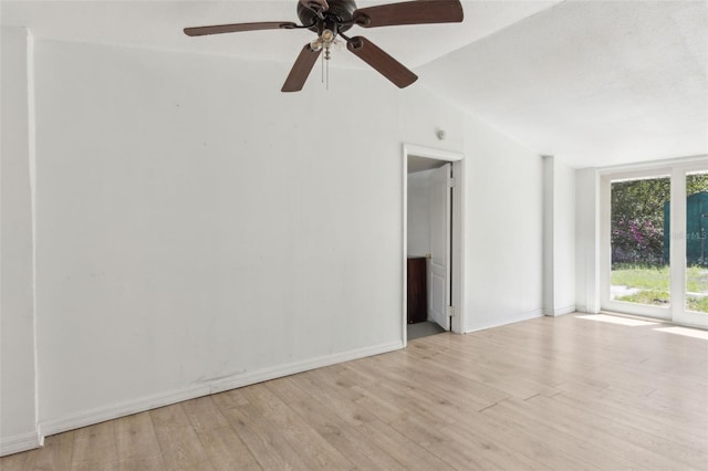 spare room featuring baseboards, vaulted ceiling, and light wood finished floors