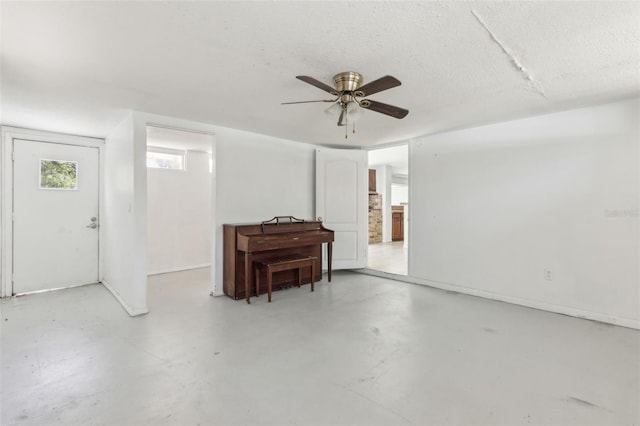 basement with a textured ceiling and ceiling fan