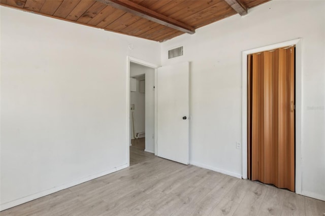 unfurnished bedroom featuring beam ceiling, visible vents, light wood finished floors, and wooden ceiling