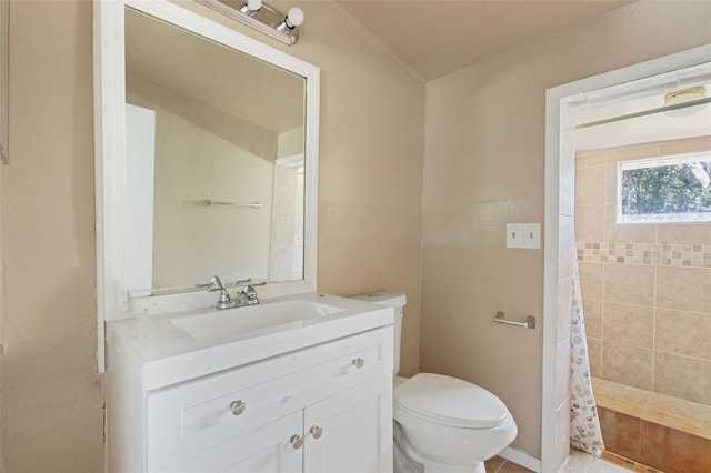 bathroom featuring tiled shower, toilet, and vanity