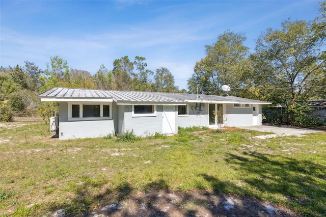 ranch-style house with concrete block siding, a front yard, and metal roof