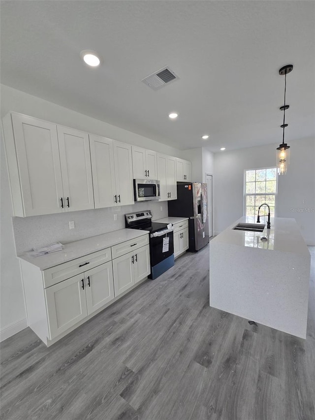 kitchen featuring stainless steel appliances, visible vents, white cabinets, a sink, and light wood-type flooring