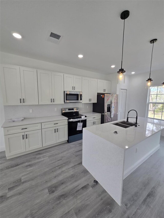 kitchen with stainless steel appliances, a sink, visible vents, and white cabinetry