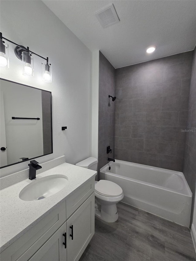 full bath featuring bathtub / shower combination, toilet, wood finished floors, vanity, and visible vents