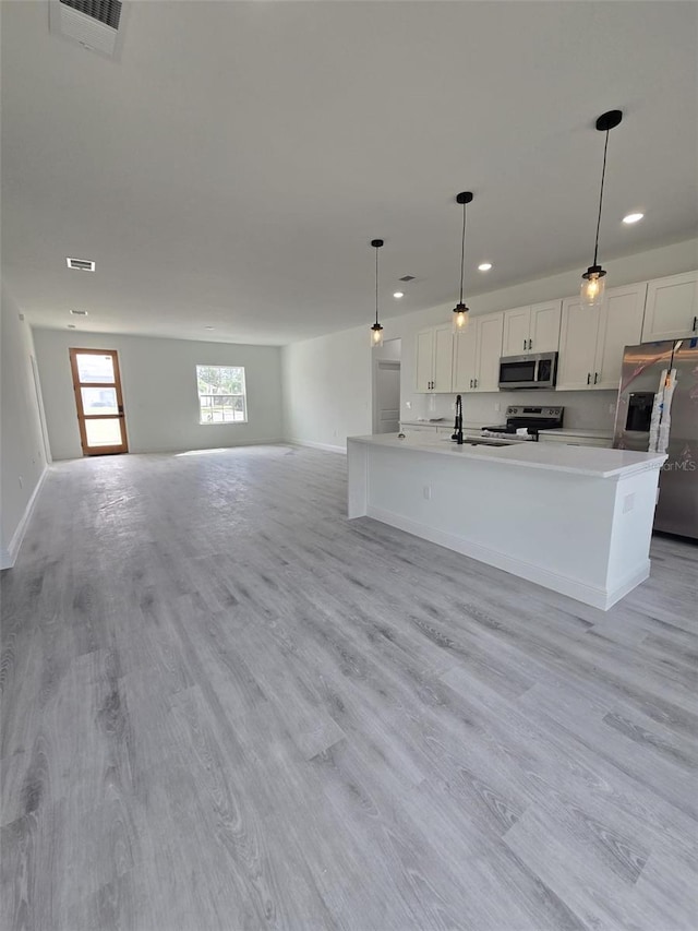 kitchen featuring visible vents, white cabinets, open floor plan, appliances with stainless steel finishes, and light wood finished floors
