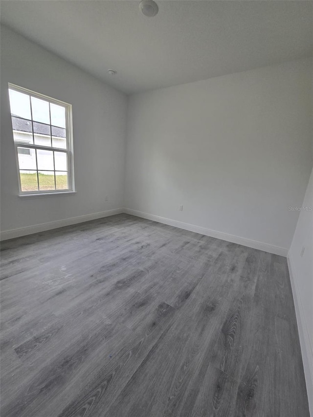 spare room with baseboards and dark wood finished floors