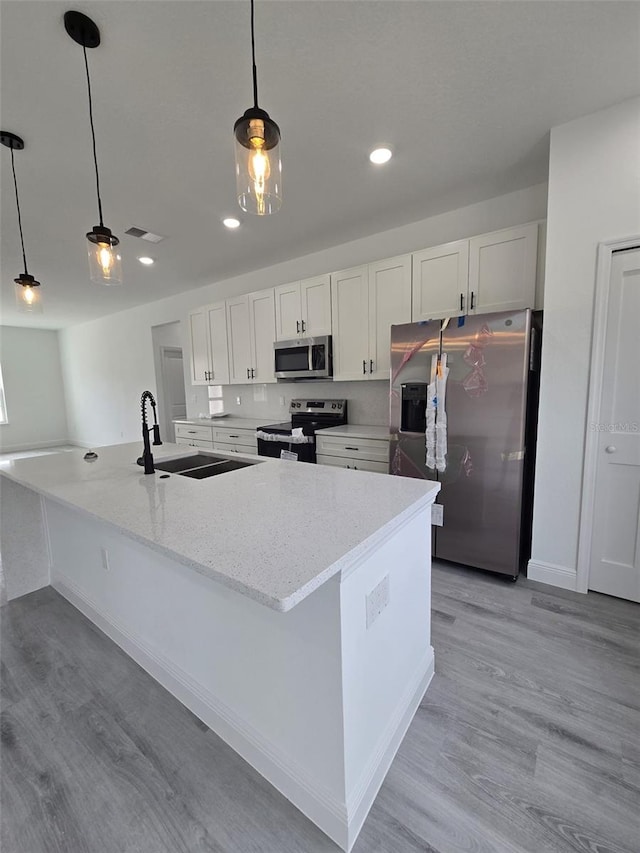 kitchen featuring white cabinets, light wood finished floors, stainless steel appliances, and a sink