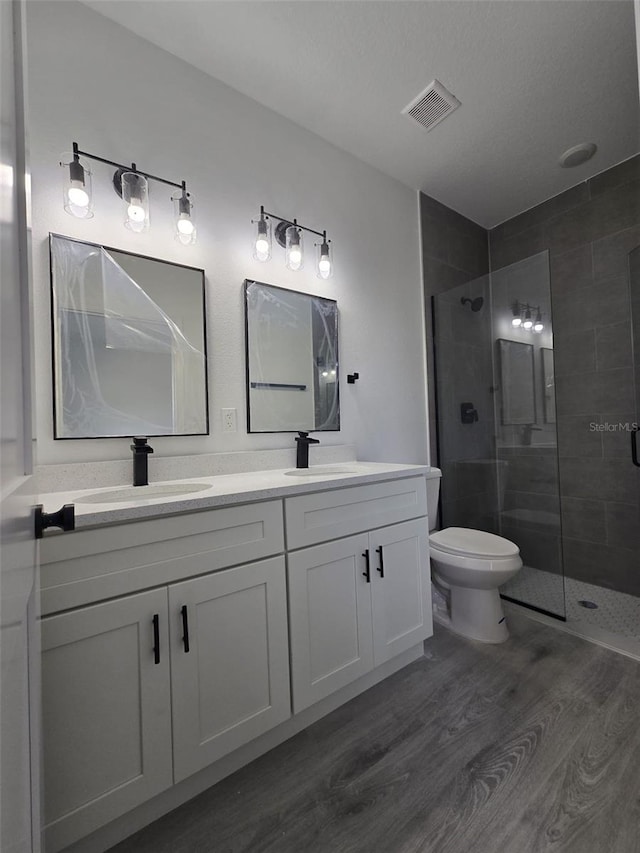 bathroom with wood finished floors, a sink, visible vents, and a shower stall