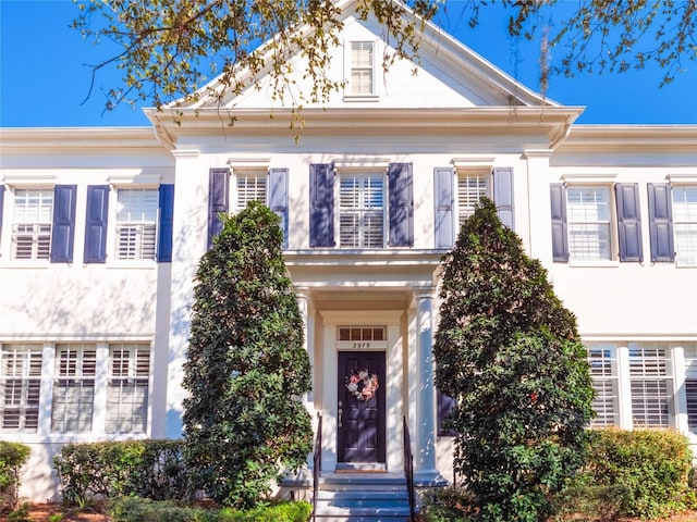 neoclassical home featuring stucco siding