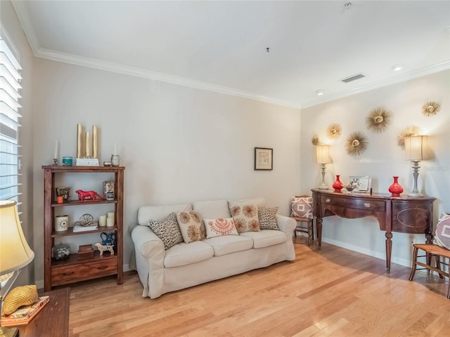 living room featuring light wood finished floors, baseboards, visible vents, and crown molding