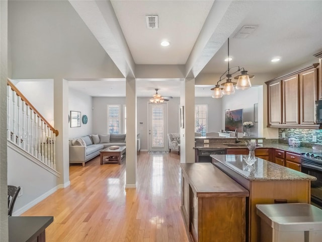 kitchen with a healthy amount of sunlight, a kitchen island, a sink, and light wood-style floors