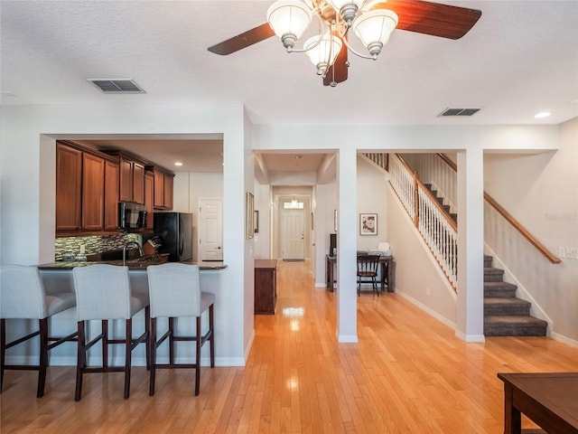 kitchen featuring freestanding refrigerator, light wood-style flooring, a breakfast bar area, and visible vents