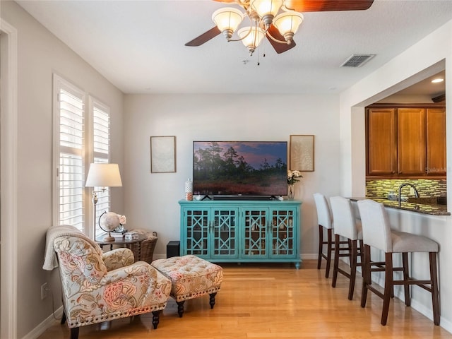 sitting room with baseboards, visible vents, ceiling fan, and light wood finished floors