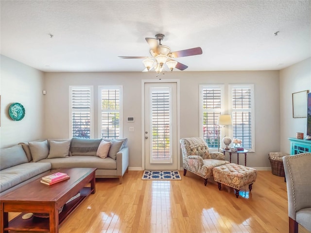 living room with baseboards, light wood-type flooring, and a healthy amount of sunlight