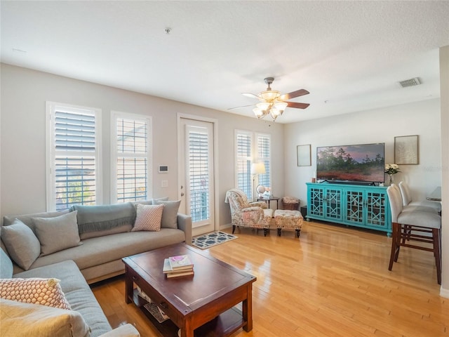 living area with visible vents, ceiling fan, and light wood finished floors