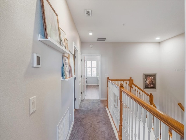 corridor with visible vents, carpet flooring, an upstairs landing, and baseboards