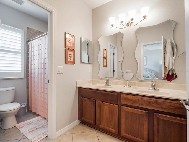 ensuite bathroom with double vanity, a sink, toilet, and tile patterned floors