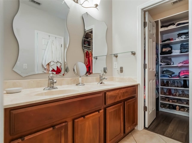 bathroom featuring tile patterned flooring, a sink, a spacious closet, and double vanity