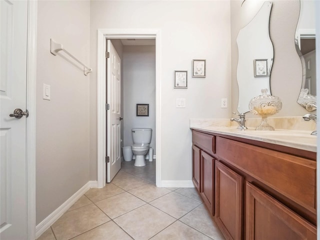 full bathroom featuring double vanity, toilet, a sink, baseboards, and tile patterned floors