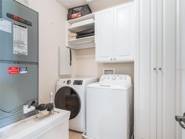 laundry room featuring light tile patterned floors, heating unit, cabinet space, and washer and dryer