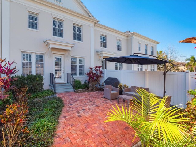 rear view of house featuring stucco siding, fence, and a patio