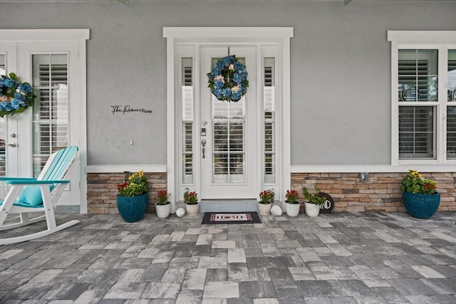 view of exterior entry with stone siding and stucco siding