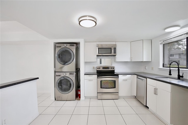 kitchen with stacked washer and dryer, appliances with stainless steel finishes, dark countertops, and a sink