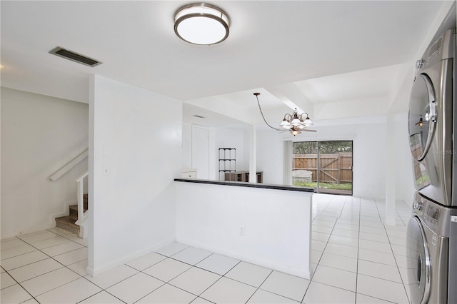 kitchen featuring light tile patterned flooring, a notable chandelier, stacked washer / dryer, visible vents, and pendant lighting