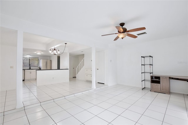 empty room with light tile patterned floors, stairway, ceiling fan with notable chandelier, and visible vents