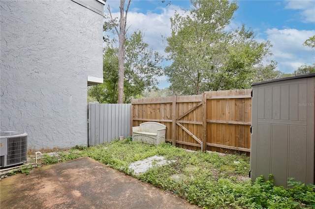 view of yard featuring a gate, a patio area, fence, and central AC unit