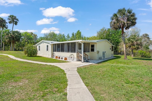 manufactured / mobile home featuring entry steps, a sunroom, and a front lawn