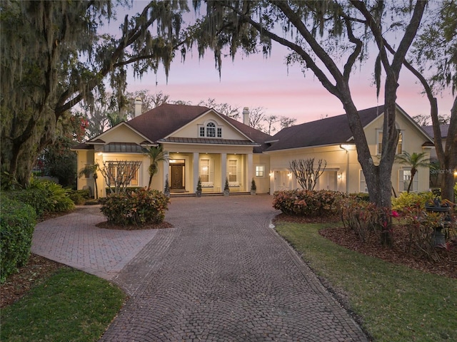 view of front facade with decorative driveway, a chimney, and stucco siding