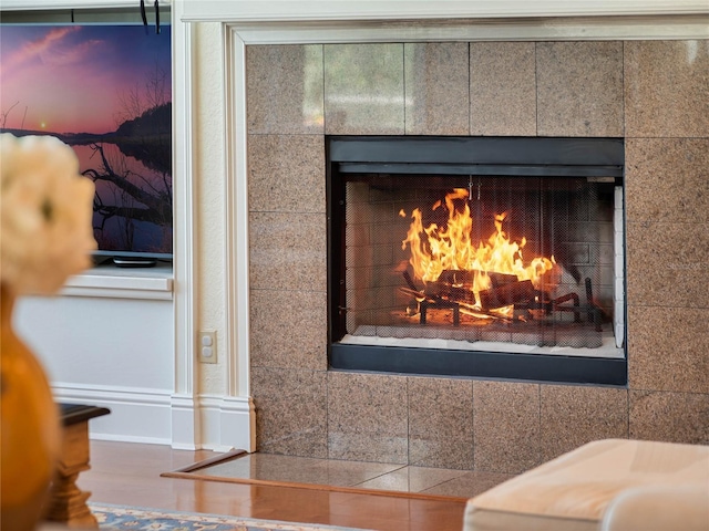 interior details with a tiled fireplace and wood finished floors