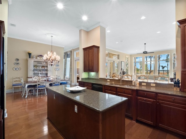 kitchen with visible vents, a kitchen island, ornamental molding, dark wood-style flooring, and a sink