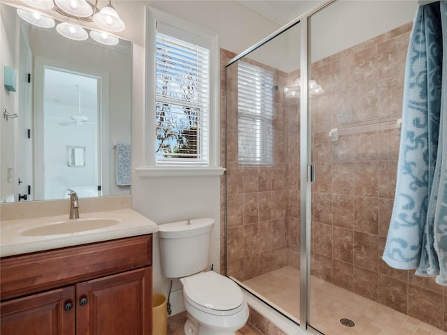 full bathroom with a stall shower, ceiling fan, vanity, and toilet