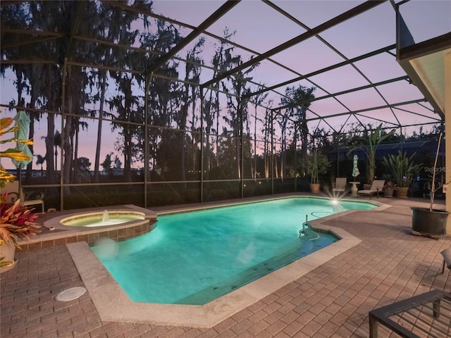 pool at dusk featuring a lanai, a pool with connected hot tub, and a patio