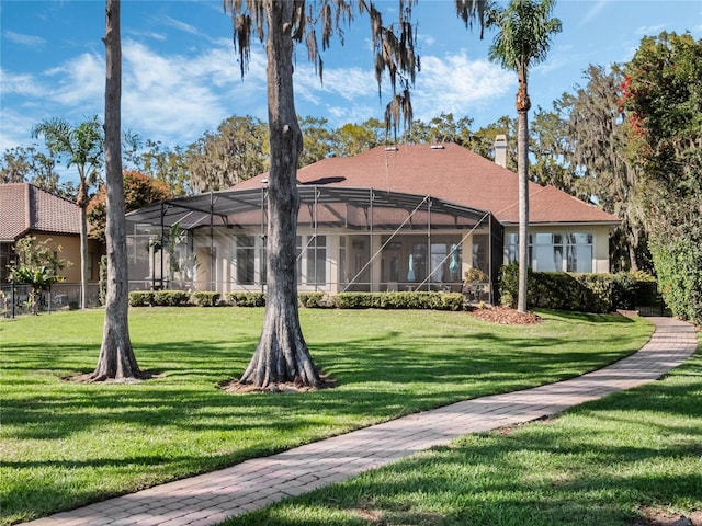 back of property featuring a chimney, a lanai, and a lawn