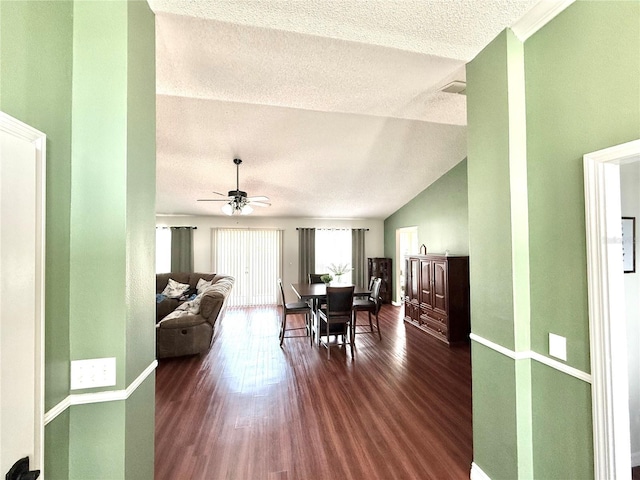 dining area with baseboards, a ceiling fan, lofted ceiling, wood finished floors, and a textured ceiling