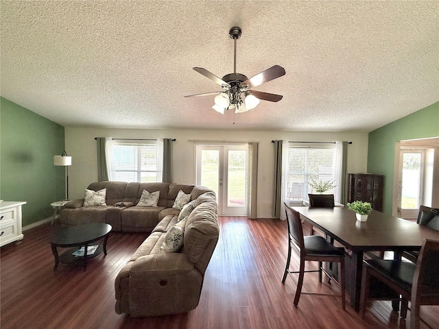 living area featuring ceiling fan, french doors, dark wood-type flooring, and a textured ceiling