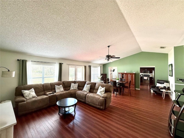 living area featuring lofted ceiling, visible vents, a ceiling fan, a textured ceiling, and wood finished floors