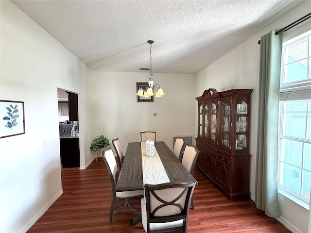 dining space with a notable chandelier, vaulted ceiling, a textured ceiling, wood finished floors, and baseboards