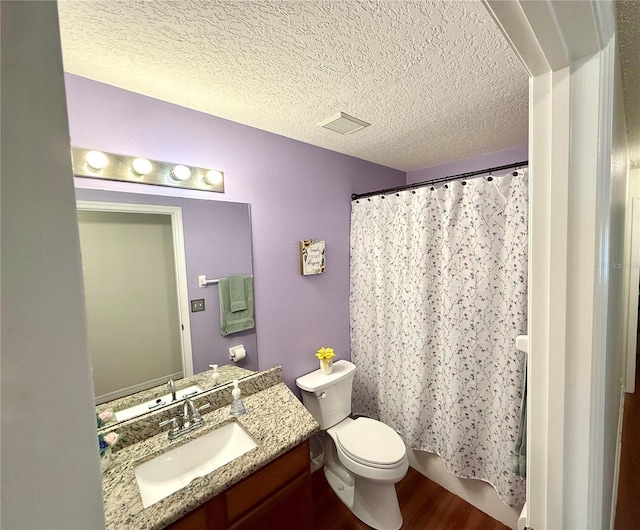 full bath featuring visible vents, toilet, wood finished floors, a textured ceiling, and vanity