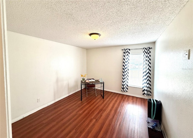 spare room with a textured ceiling, wood finished floors, and baseboards