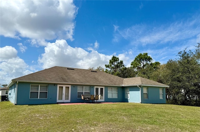 rear view of house with a yard, roof with shingles, stucco siding, and french doors