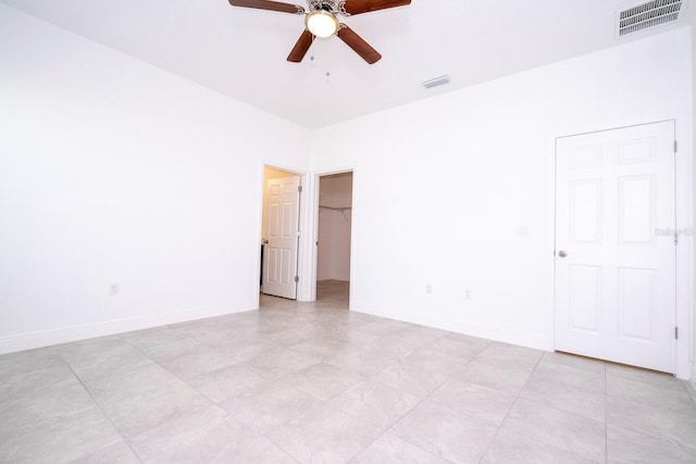 unfurnished room with a ceiling fan, visible vents, and baseboards