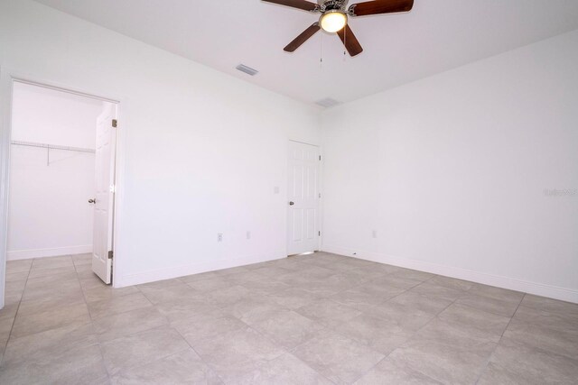 empty room featuring a ceiling fan, visible vents, and baseboards