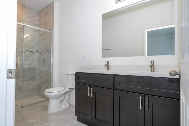 full bathroom featuring double vanity, a stall shower, a sink, and toilet